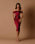 Woman wearing a burgundy off-shoulder dress against a brown background