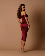 Woman wearing a burgundy off-shoulder dress against a brown background