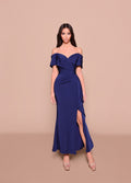 Woman wearing a blue off-shoulder dress with a slit on a beige background