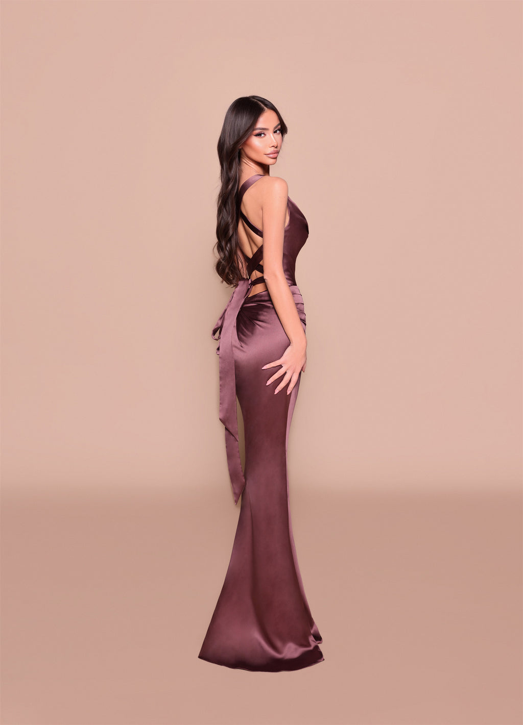 Woman wearing a long, elegant brown dress against a beige background