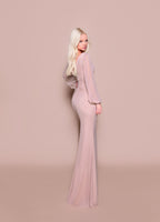 Woman wearing a long, light pink dress against a matching background