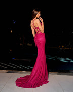 Woman in a pink evening gown with a long train at night.