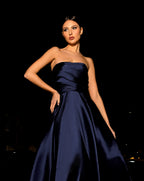 Woman wearing a strapless navy blue gown against a dark background