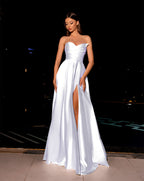 Woman wearing a white strapless gown with a high slit on a dark background
