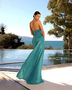 Woman in a teal evening gown standing by a pool with a scenic background