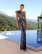 Woman in a navy and silver evening gown standing by a pool with a scenic background