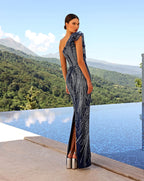 Woman in a patterned evening gown standing by a pool with mountains in the background