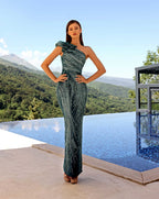 Woman in a green evening gown standing by an infinity pool with a scenic background