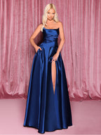 Woman wearing a blue evening gown with a slit on a pink background
