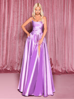 Woman wearing a purple evening gown against a pink curtain background