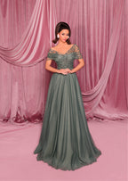 Woman in a green evening gown standing against a pink curtain backdrop