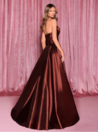 Woman wearing a burgundy strapless gown against a pink curtain background