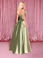 Woman wearing a green strapless gown against a pink curtain backdrop