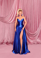 Woman in a blue evening gown with a high slit standing against a pink draped curtain.