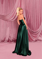 Woman in a green evening gown against a pink draped curtain backdrop
