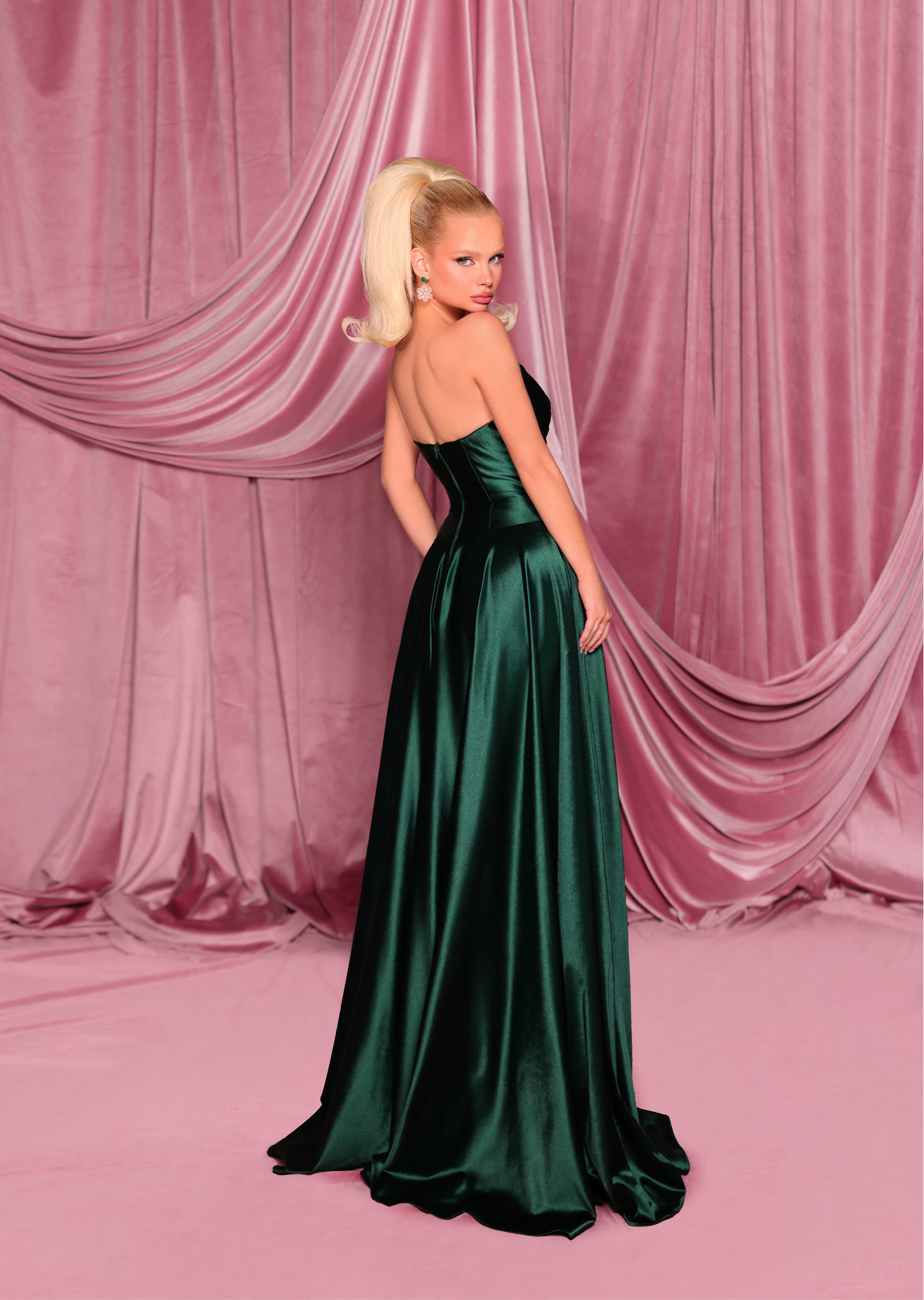 Woman in a green evening gown against a pink draped curtain backdrop