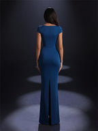 Woman wearing a blue evening gown with a slit on a dark background