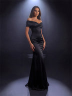 Woman wearing a black off-shoulder gown against a dark background