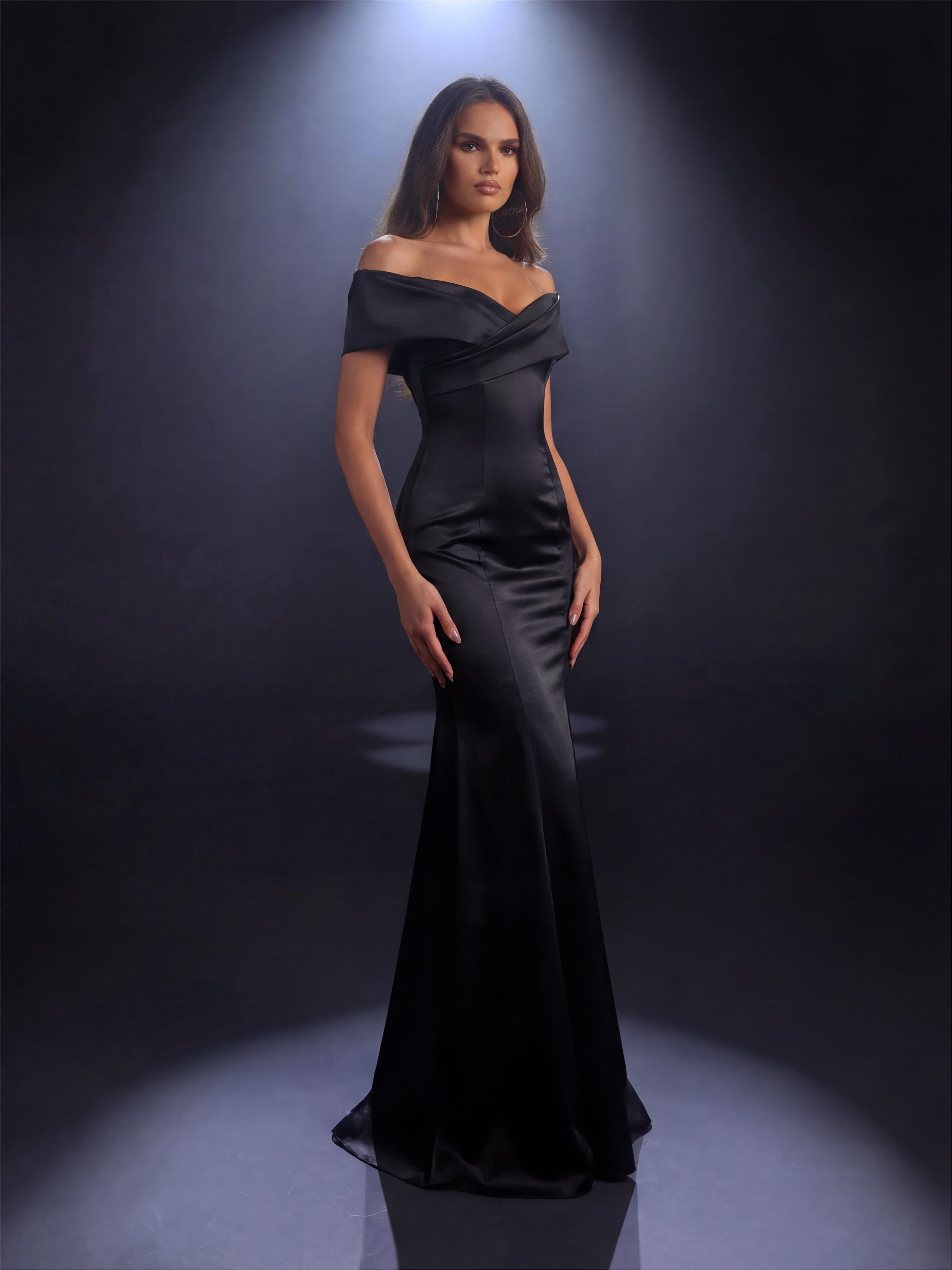 Woman wearing a black off-shoulder gown against a dark background