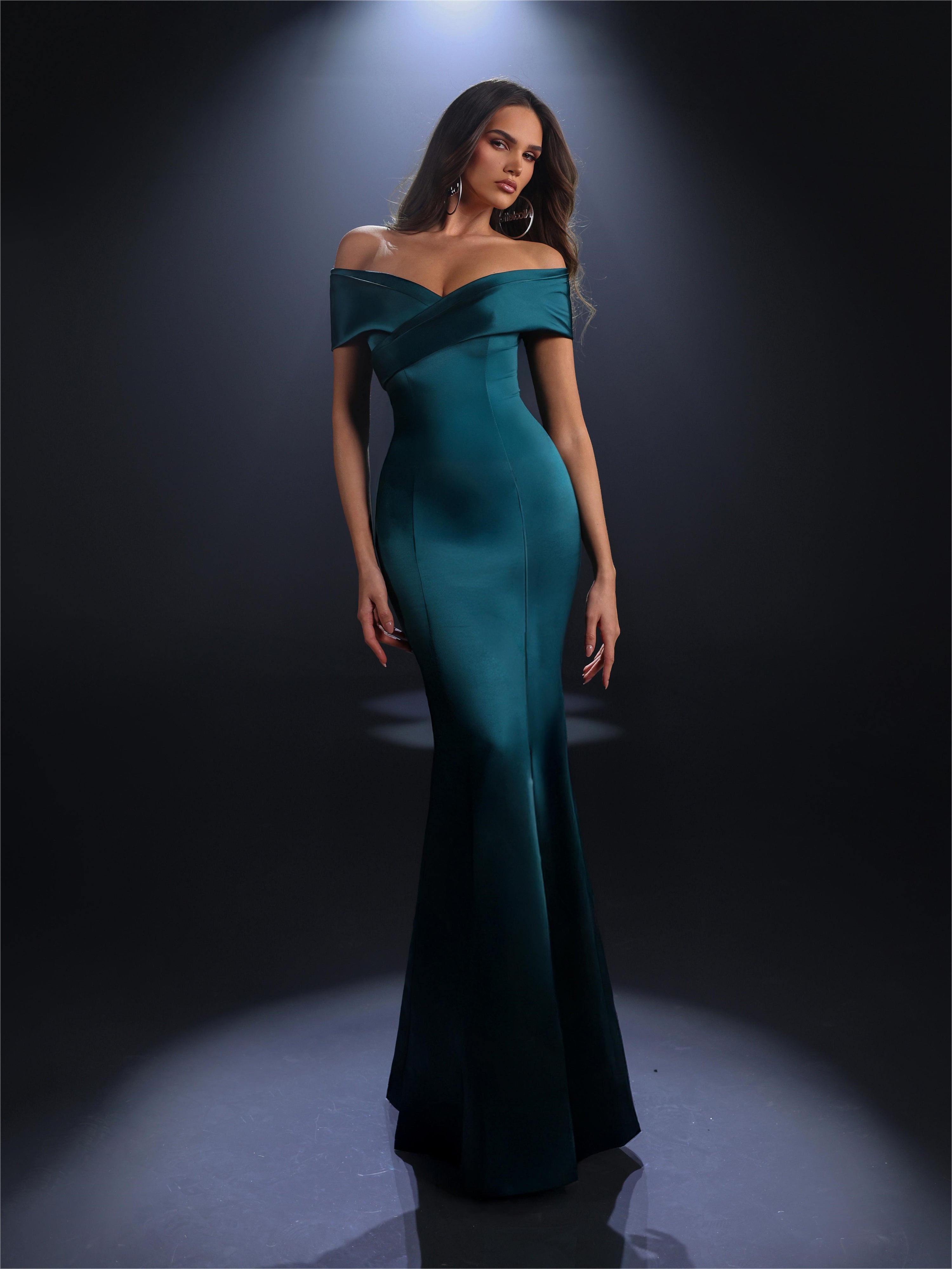 Woman wearing a teal off-shoulder gown against a dark background