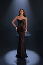 Woman wearing a dark brown strapless gown against a black background