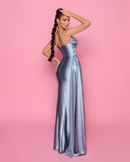Woman in a silver evening gown against a pink background