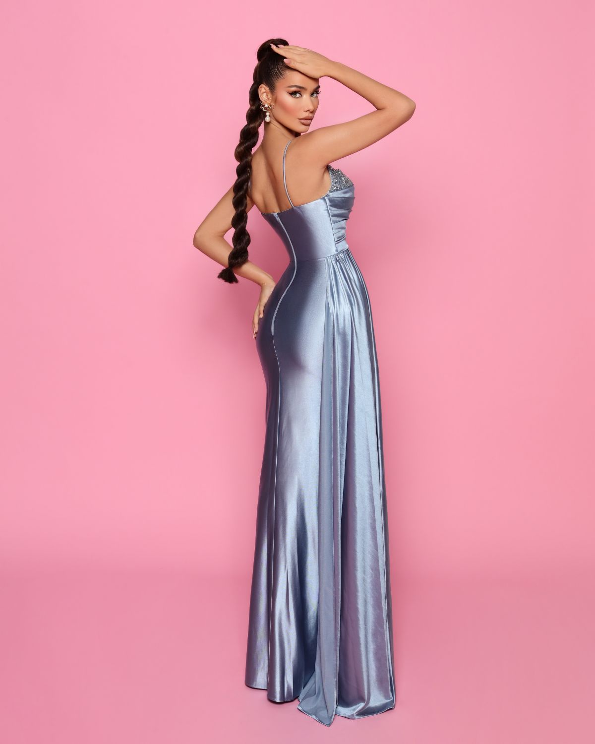 Woman in a silver evening gown against a pink background