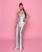 Woman wearing a silver evening gown with a pink background