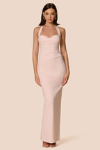 Woman wearing a pink halter neck dress against a beige background