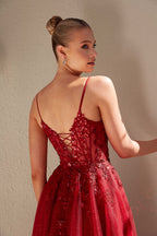 Woman wearing a red evening gown with intricate detailing against a beige background