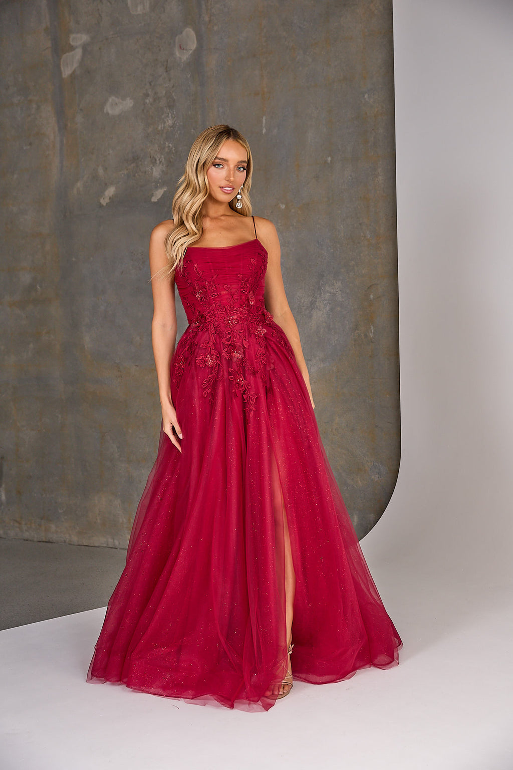Woman wearing a red evening gown with a textured gray background