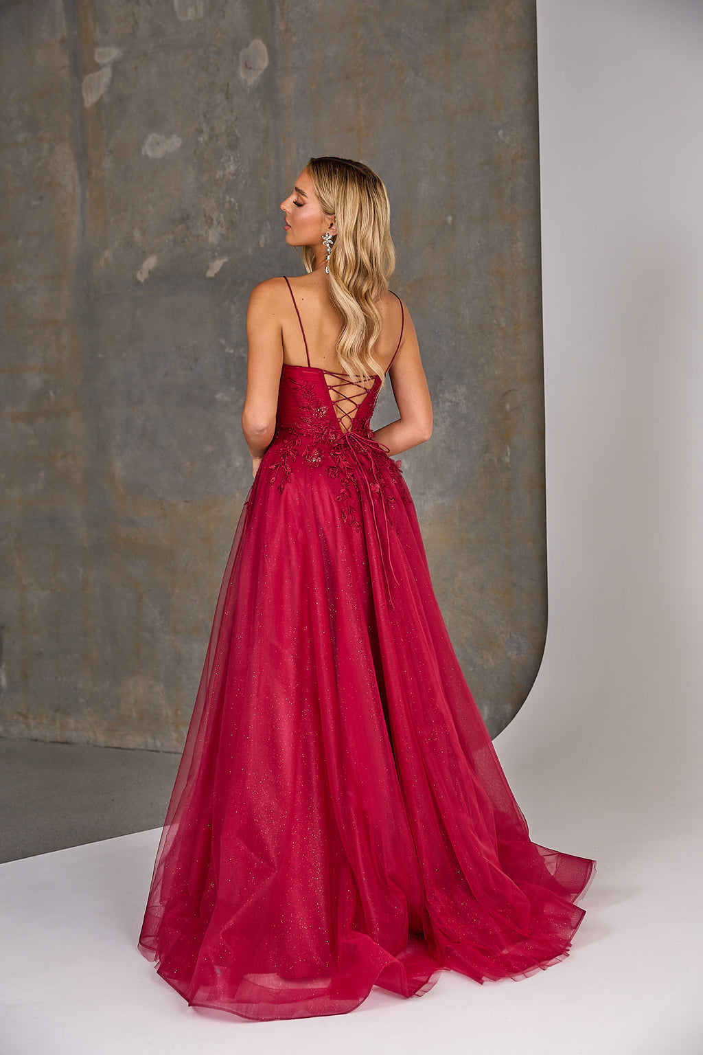 Woman wearing a red evening gown with a textured wall background