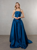 Woman wearing a blue gown against a plain background
