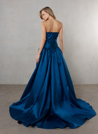 Woman wearing a blue strapless gown against a plain background