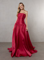 Woman wearing a strapless red gown against a plain background