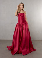 Woman wearing a strapless red gown against a plain background