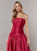 Woman wearing a strapless red dress against a plain background