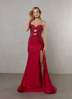 Woman wearing a red strapless evening gown with cut-out details and a high slit on a plain background