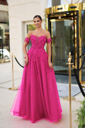 Woman in a pink evening gown standing in front of a building entrance.
