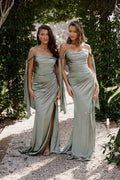 Two women in matching silver dresses standing outdoors with greenery in the background