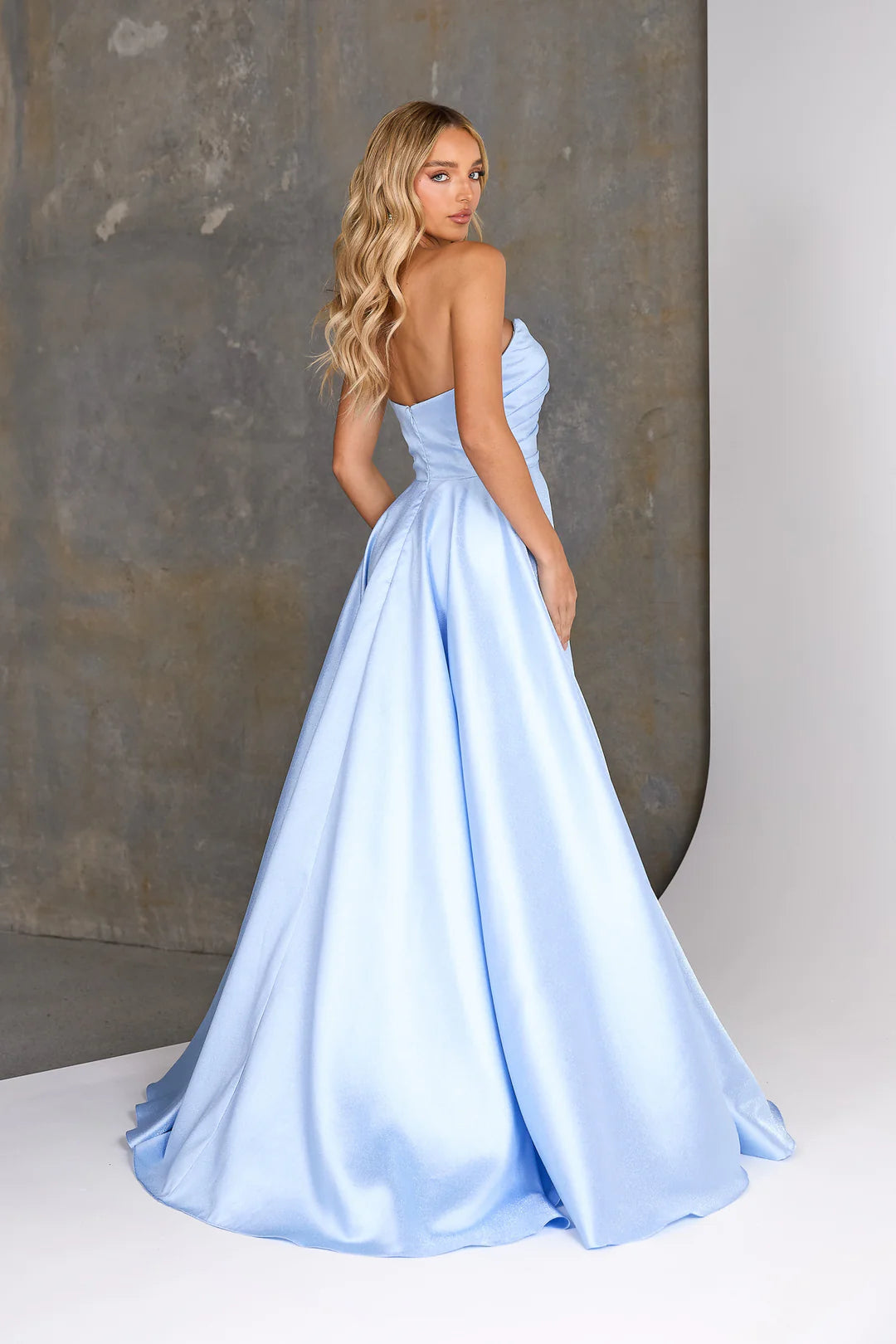 Woman wearing a light blue evening gown against a neutral background
