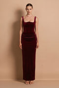 Woman wearing a burgundy velvet dress against a beige background