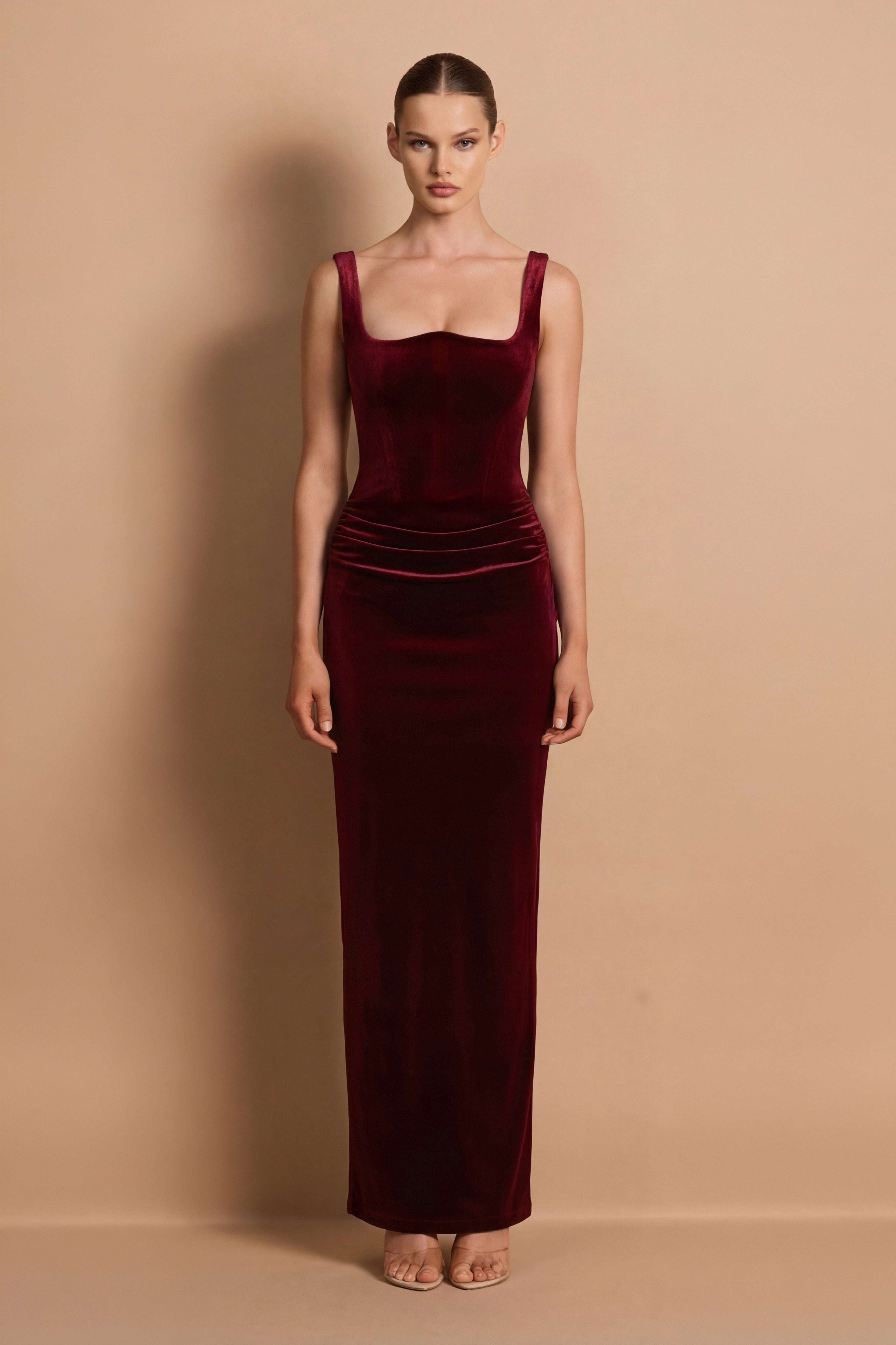Woman wearing a burgundy velvet dress against a beige background