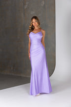 Woman wearing a long lilac dress against a neutral background
