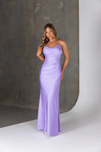 Woman wearing a long purple dress against a neutral background