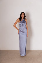 Woman wearing a light blue satin one-shoulder gown against a plain background