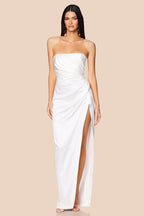 Woman wearing a strapless white gown with a slit on a beige background