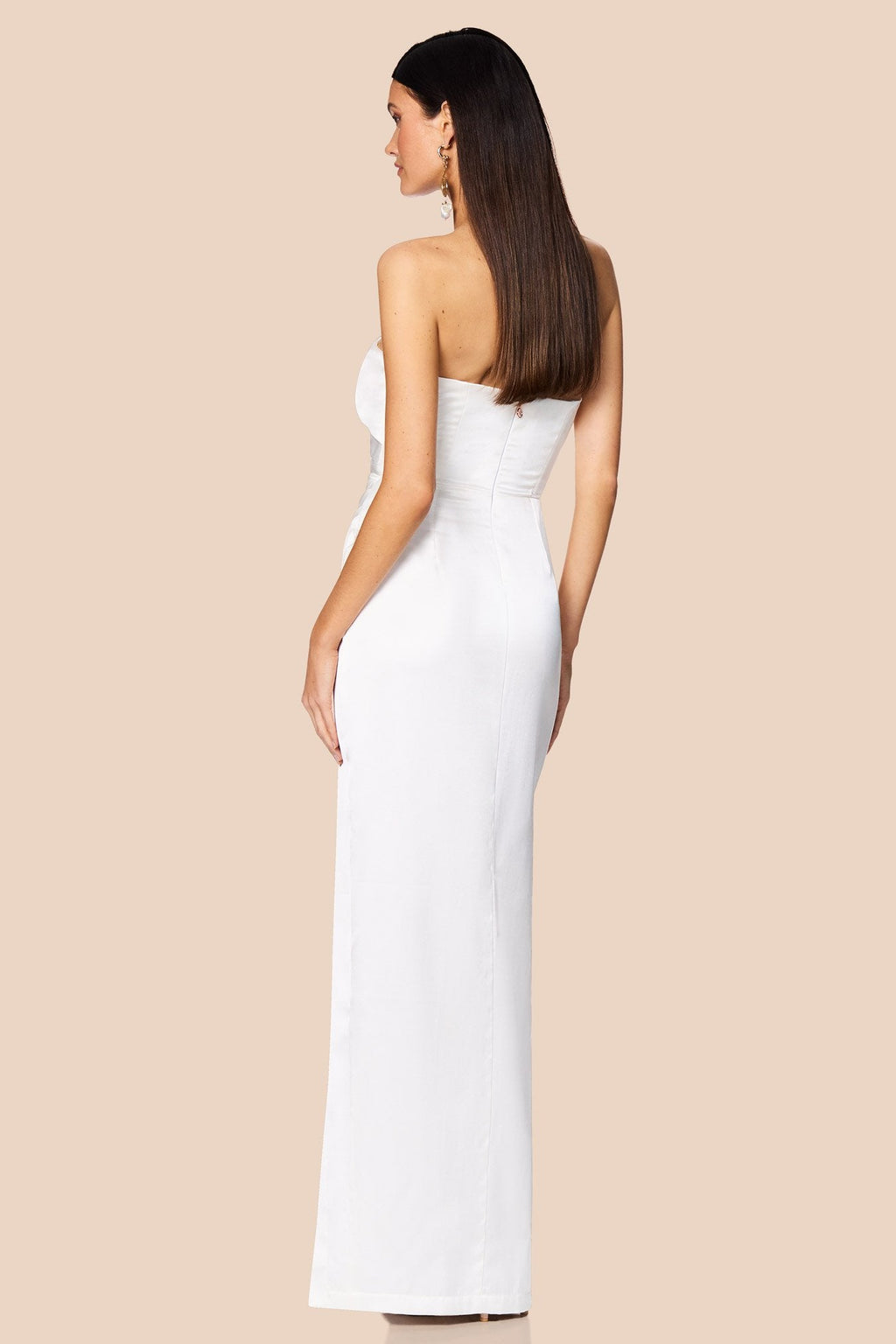 Woman wearing a strapless white dress on a beige background