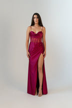 Woman wearing a vibrant red evening gown with a high slit on a white background