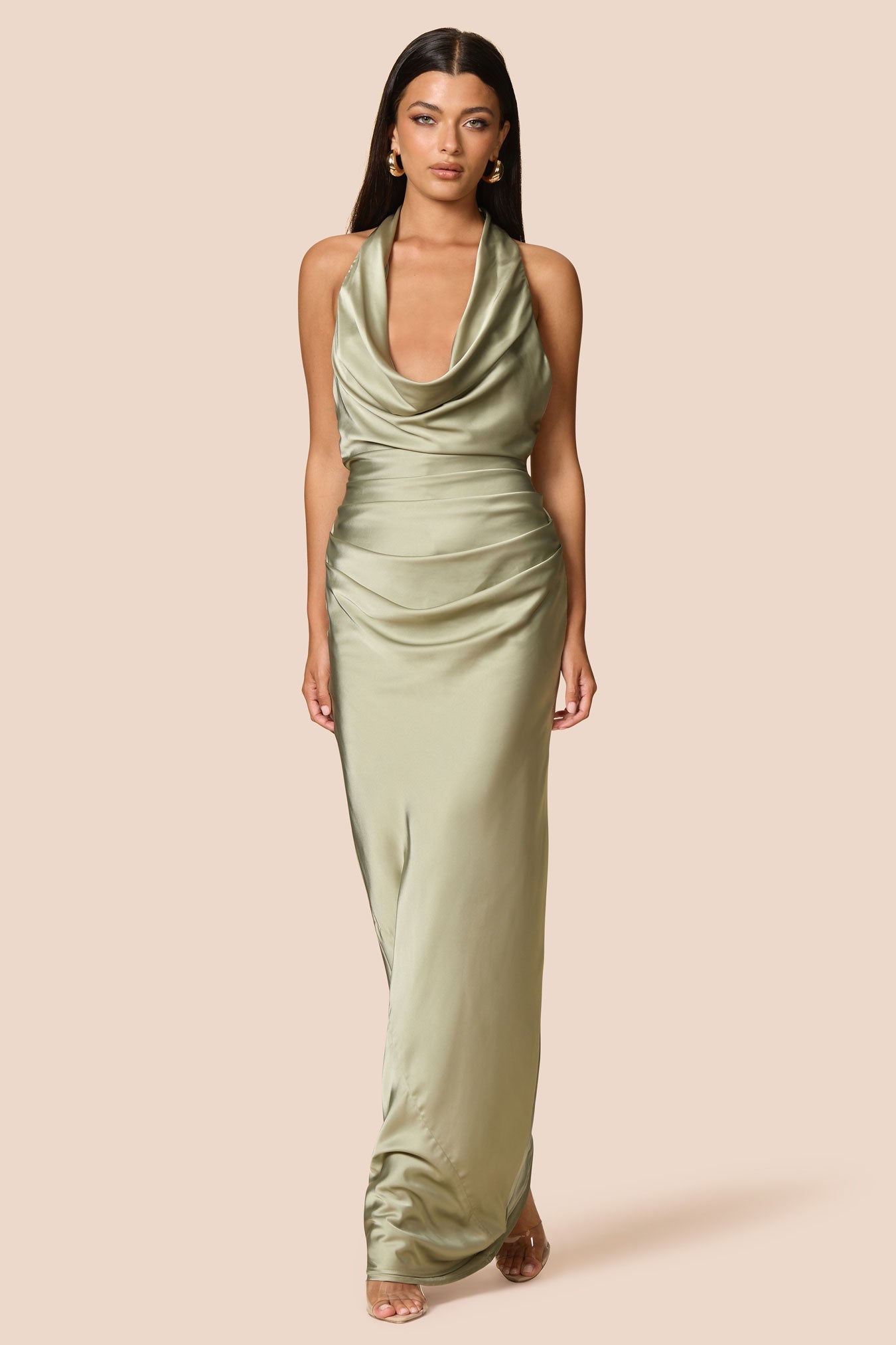 Woman wearing a green halter neck dress on a beige background